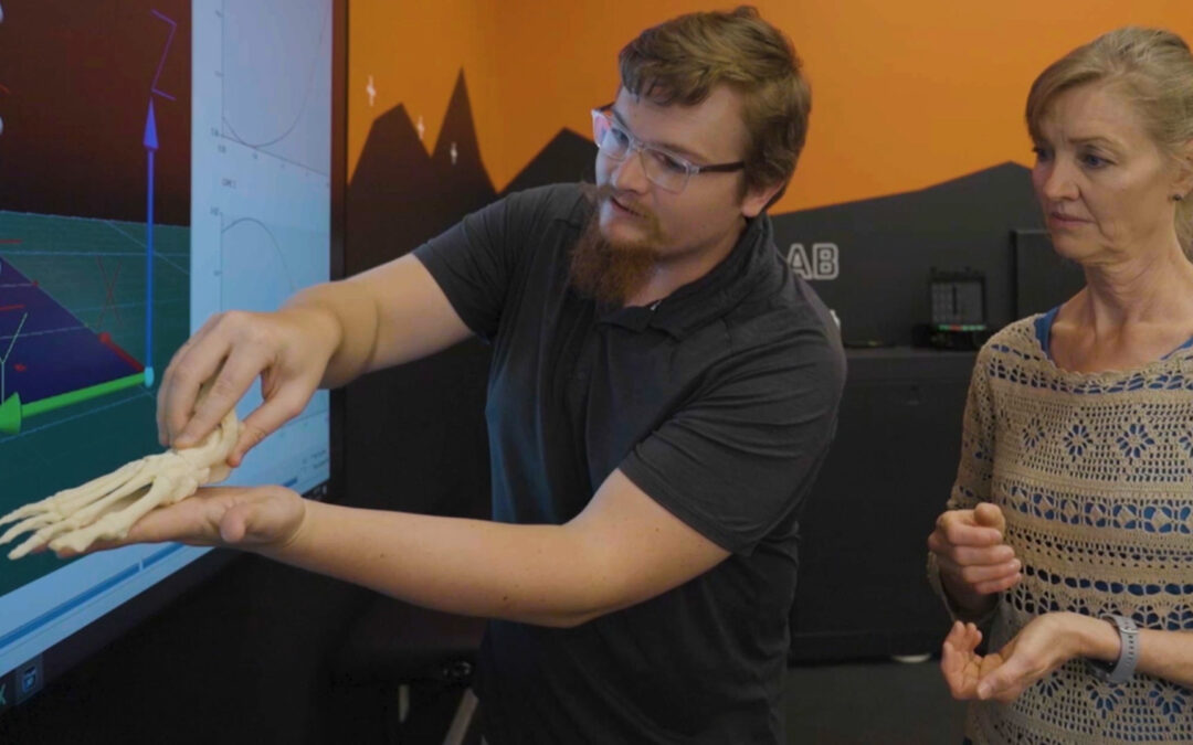 Two biomechanists, one male and one female, analyzing a skeletal human foot.
