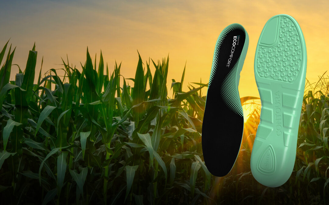 A pair of green INSITE EcoComfort shoe insoles against a cornfield at sunset.